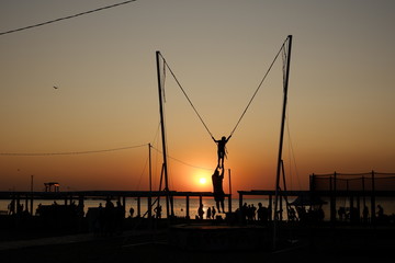Trampoline jumping with ropes during sunset at the Black Sea in Anapa,  Russia.
