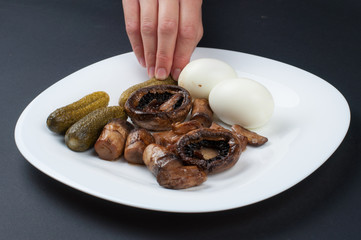 Mushrooms and boiled eggs on a white plate isolated on a black background.Natural food