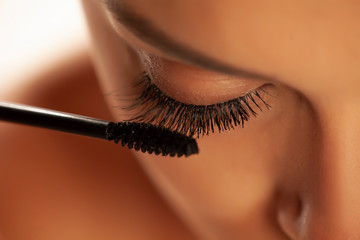 closeup of woman applying mascara on her eyelashes
