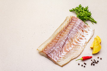 Raw pollock (Pollachius virens) fillet. Fresh fish for healthy food lifestyle. Lemon, parsley, sea...