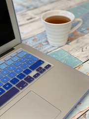 Working desk with laptop and cup of tea 