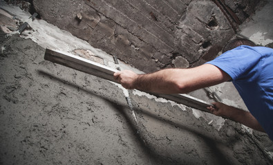 Worker holding level tool. Plastering wall. Construction work