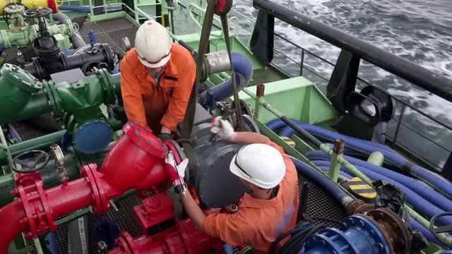 oil tanker Onyx motorman-pump and sailor connect fuel pump meter to pipeline using wrench during heavy pitching