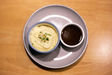Mashed potatoes in bowl with pepper-cream gravy sauce top view. 