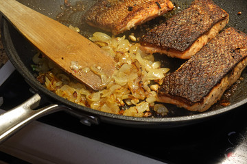 Roasting salmon and onion in frying pan.