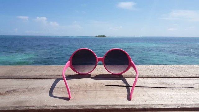 pink sunglasses on bench in seashore of malaysia