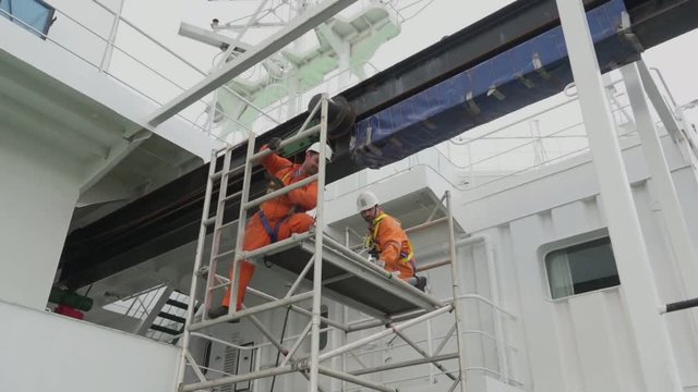 tanker Onyx electrical engineer and bosun change lubricating oil in hoist gear standing on ladder ground at pitching