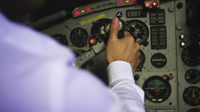 Captain airline pilot in vintage plane pulling control steering wheel yoke to take off.