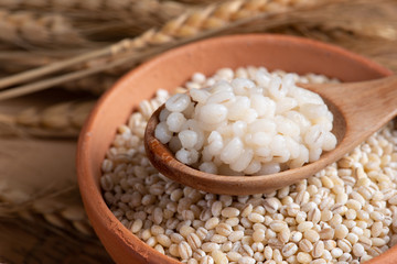 Cooked peeled barley grains in wooden bowl