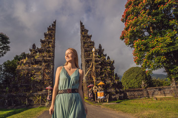 Tourist woman walking through Traditional Balinese Hindu gate Candi Bentar close to Bedugul, Bratan lake Bali island Indonesia. Vacation on Bali