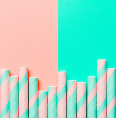 Striped paper straws on pink and blue-green background. Ecology product. Equipment for single use. Plastic alternative. Zero waste concept. Copy space for text or design. Top view or flat lay. Square.