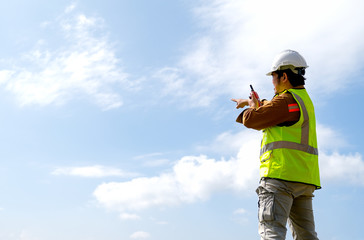 Naklejka premium Engineer manager man with white helmet use fm handheld transceiver or walkie talkie to communicate and point to the sky.