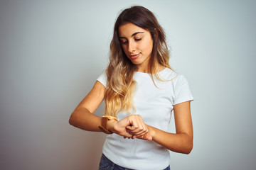 Obraz premium Young beautiful woman wearing casual white t-shirt over isolated background Checking the time on wrist watch, relaxed and confident