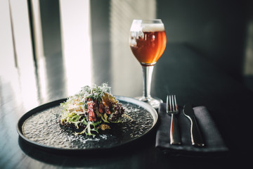 Healthy and delicious beef sandwich on dark table with glass of beer at restaurant, chef making food.