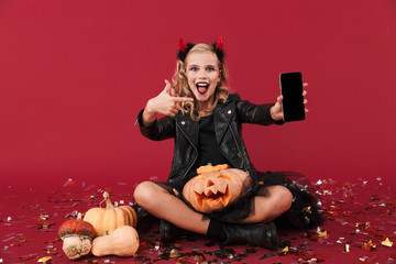 Obraz na płótnie Canvas Devil in carnival halloween costume showing display of phone.