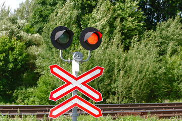 Red light at a railway level crossing. Train is approaching a road junction. Warning signal at railway crossing. Traffic light with flashing red signal on railway