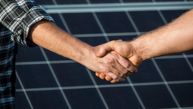 Handshake Of Two Businessmen On A Background Surface Of Solar Panels