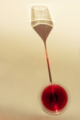 Glass of red wine on a light background. A spectacular long shadow falls from the glass. The original concept of alcoholic drinks, varieties of wine. Minimalism, top view. Copy space.