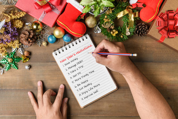 Hand man writing New year resolution on note paper