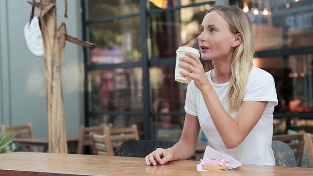 Young stylish woman drinking coffee outdoors at the cafe