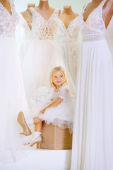 small, cute girl in the bridal salon tries on clothes and shoes