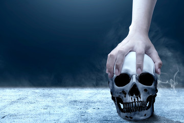 Hand holding human skull above the floor