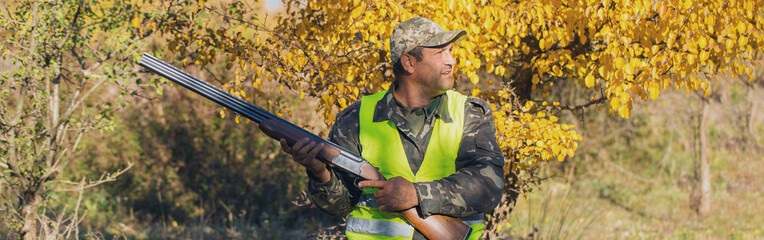 Silhouette of a hunter with a gun in the reeds against the sun, an ambush for ducks with dogs	