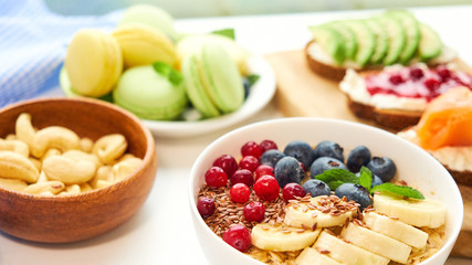 breakfast top view white background. oatmeal with berries, toasts on a wooden tray, nuts, coffee