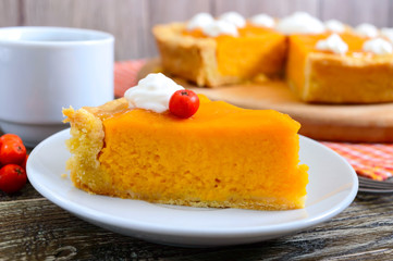 Piece of traditional homemade pumpkin pie and a cup of coffee on a wooden table. Healthy food, dessert for gourmets. Thanksgiving theme. Traditional autumn baking.