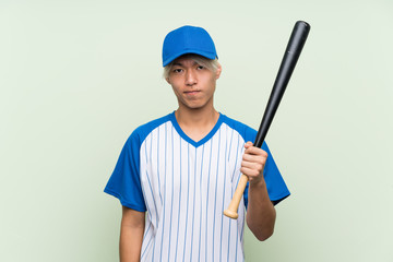 Fototapeta premium Young asian man playing baseball over isolated green background with sad expression