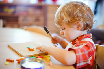 Little cute toddler boy playing with wooden puzzle hammer toys. Happy baby child playing at playschool or kindergarten. children at day care doing activity