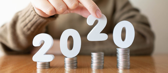 2020 New year saving money and financial planning concept. Female hands putting white number 2020...