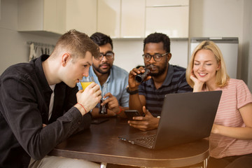 Group of young people sitting at table using laptop