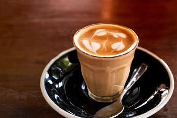 Hot latte in a clear glass on a wooden table