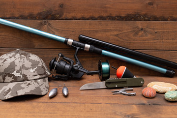 Fishing rod and other fishing tools and tools. There is a  wooden background.