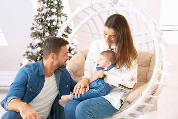 Smiling young family enjoy spending time with their cute baby girl during Christmas