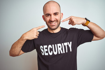 Young safeguard man wearing security uniform over isolated background smiling cheerful showing and pointing with fingers teeth and mouth. Dental health concept.