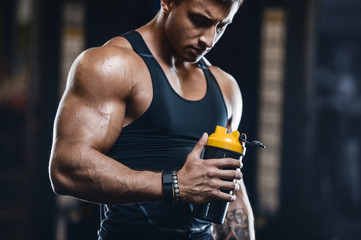 Fototapeta na wymiar Sport muscular fitness man drinking water after workout cross fitness and bodybuilding concept gym background abs muscle exercises in gym naked torso fitness concept ..