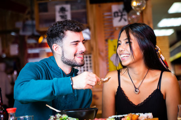 tow young couple asiatic and European eating in japanese restaurant