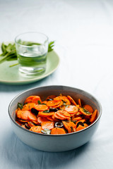 Traditional Moroccan cooked carrot salad North African vegan dish with chopped parsley and olives on gray plate copy space.Healthy organic food for holiday dinner.Vertical orientation