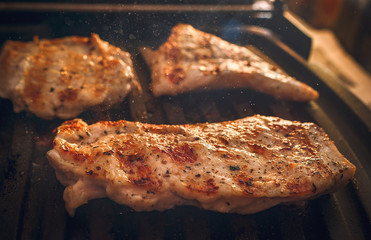 Roasting Fuming Chicken or Turkey Meat Fillets Seasoned with Spices on Electric Grill Plate.