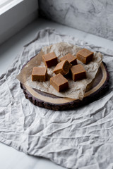 Fresh caramel fudge candies on a wooden plate with copy space in marble background