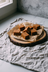 Fresh caramel fudge candies on a wooden plate with copy space in marble background