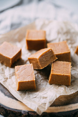 Fresh caramel fudge candies on a wooden plate with copy space in marble background