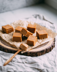 Fresh caramel fudge candies on a wooden plate with copy space in marble background