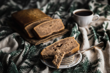 Sliced banana bread, a cup of black coffee, a piece of cake on the fork. Horizontal image