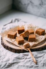 Fresh caramel fudge candies on a wooden plate with copy space in marble background