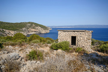 Fototapeta na wymiar the highest point of Punta Giglio in the Mediterranean coast of Sardinia. In the foreground the remains of a fascist war post from World War II and in the background the city of Alghero