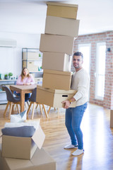 Fototapeta na wymiar Young couple moving to a new house, man holding cardboard boxes worried about falling for overweight