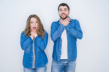 Young beautiful couple standing together over white isolated background shouting and suffocate because painful strangle. Health problem. Asphyxiate and suicide concept.